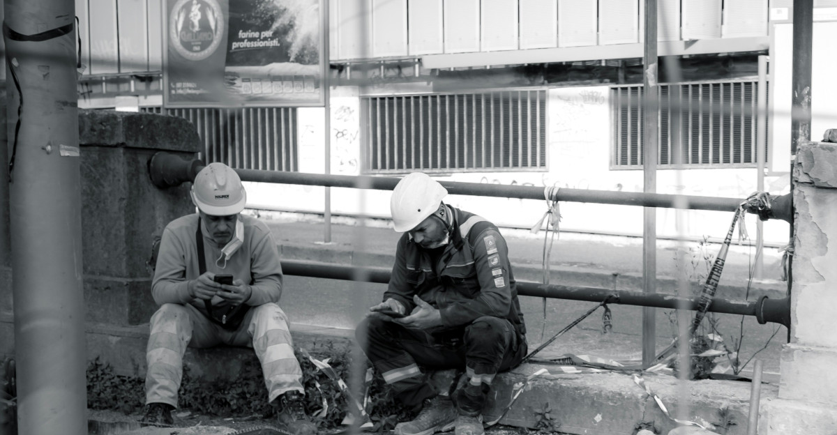man in black jacket sitting on concrete wall