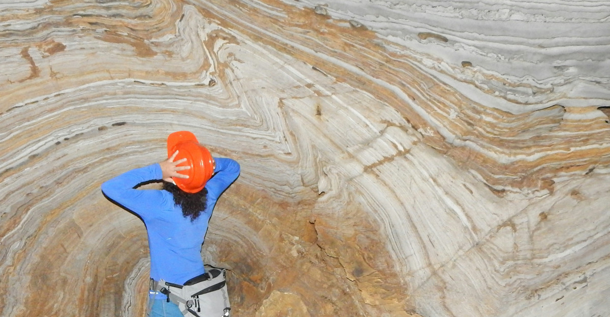 man in blue jacket and blue denim jeans standing on brown rock formation during daytime
