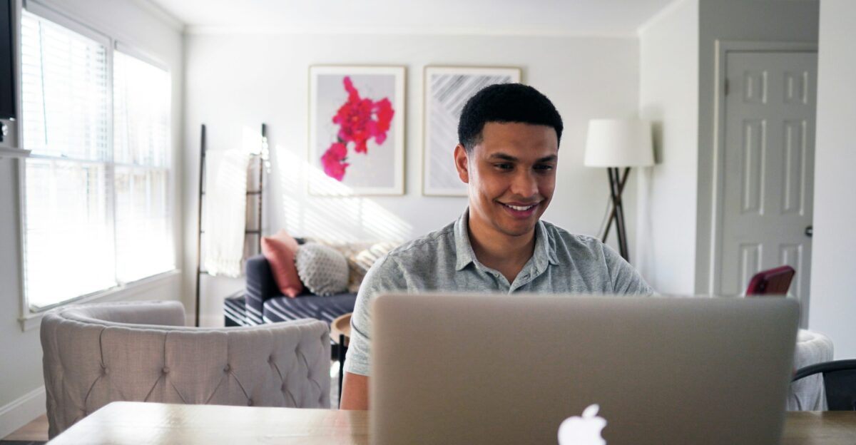 man in gray hoodie sitting on chair in front of silver macbook