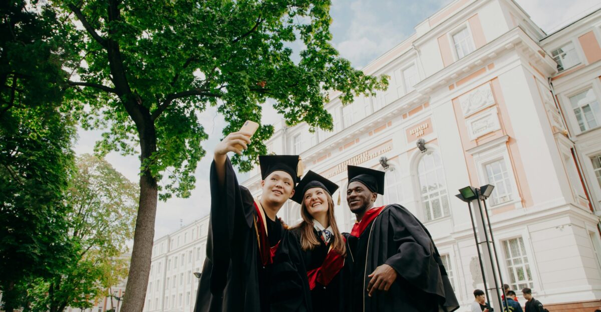women in black academic dress standing near green tree during daytime