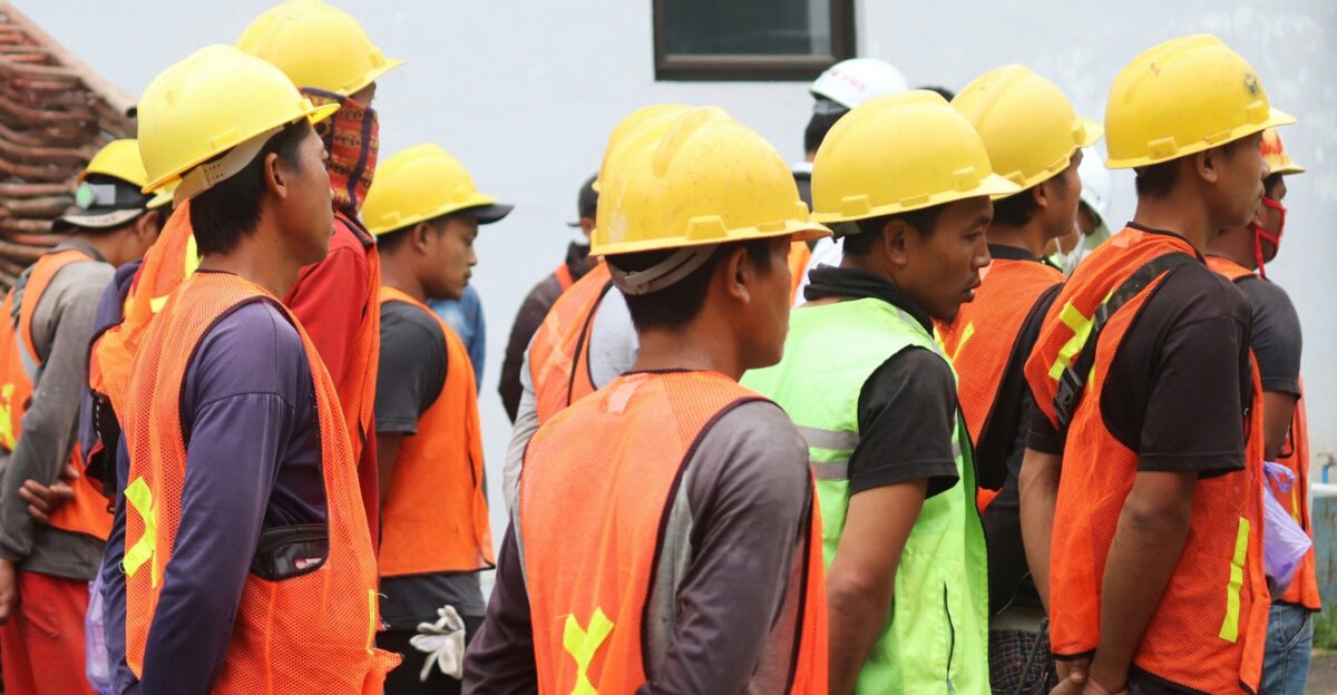 man in orange vest wearing yellow hard hat