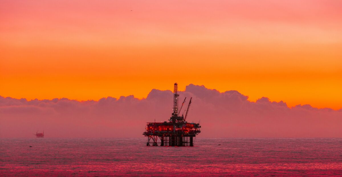 an oil rig in the middle of the ocean at sunset