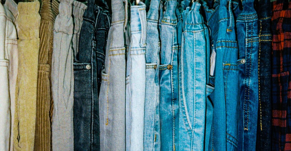 a rack of different colored jeans hanging from hooks
