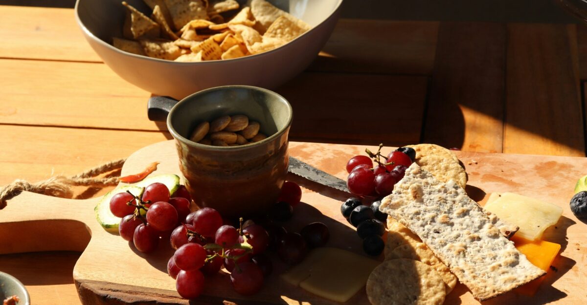 a wooden cutting board topped with grapes and crackers