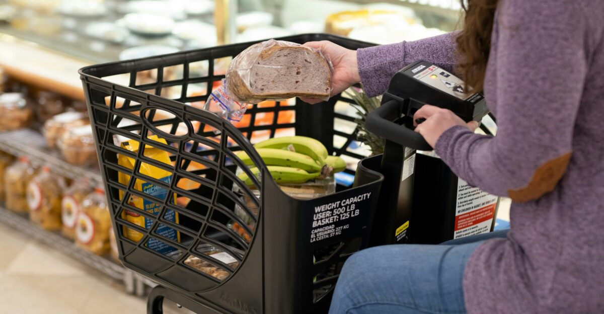 a woman sitting in a grocery cart with a sandwich in her hand