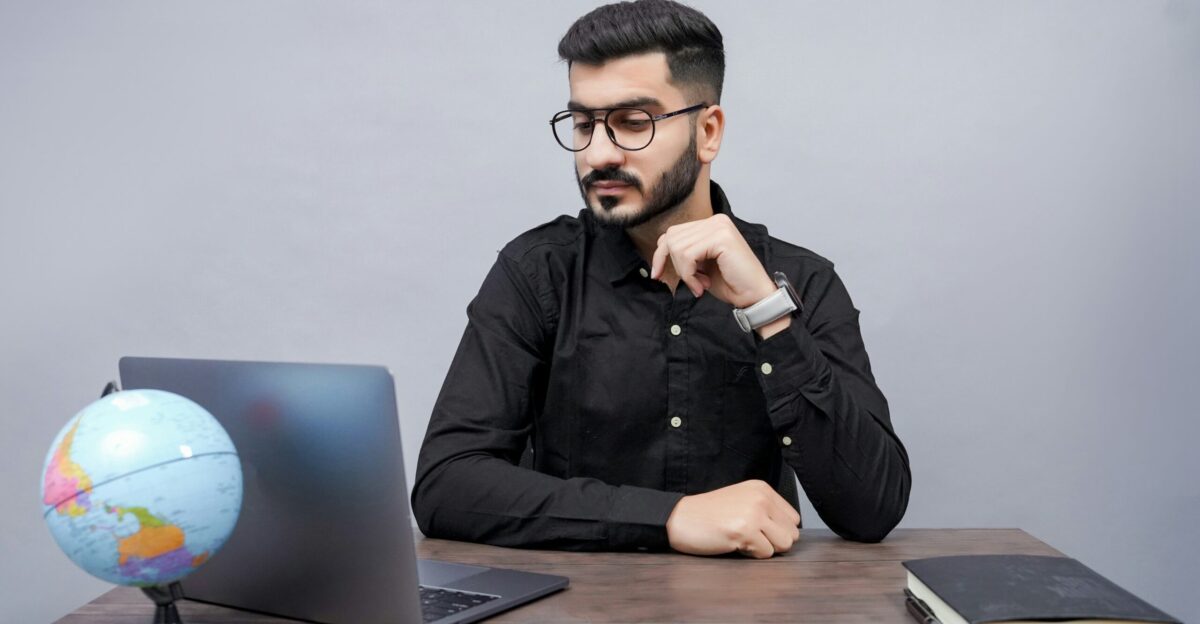 a man sitting at a desk with a laptop and a globe