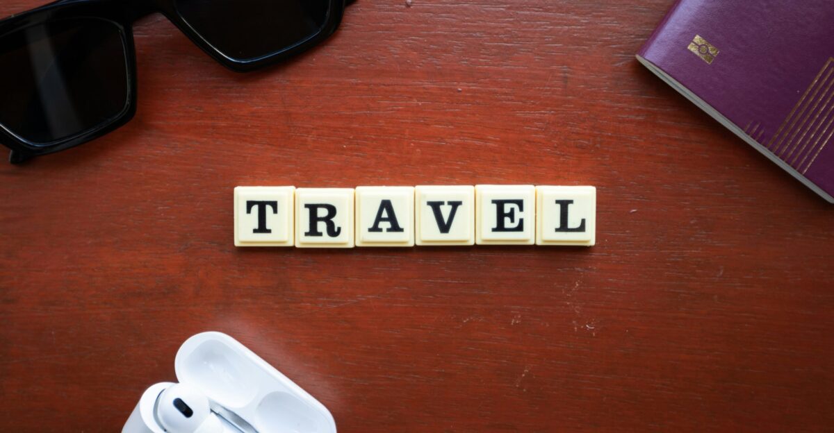 the word travel spelled with scrabbles on a wooden table