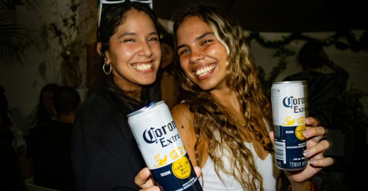 two women holding cans of corona energy drink