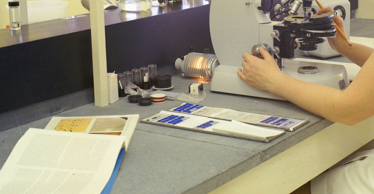 a woman looking through a microscope in a laboratory