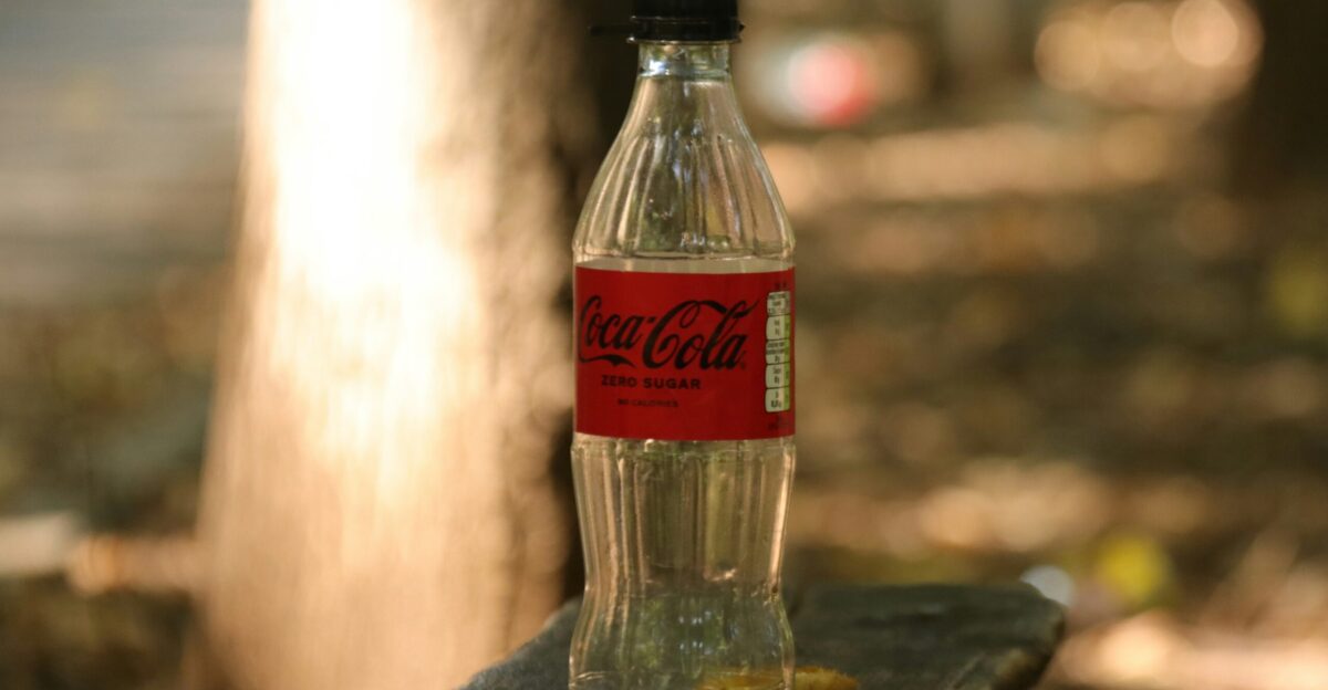 a bottle of coca cola sitting on top of a wooden bench