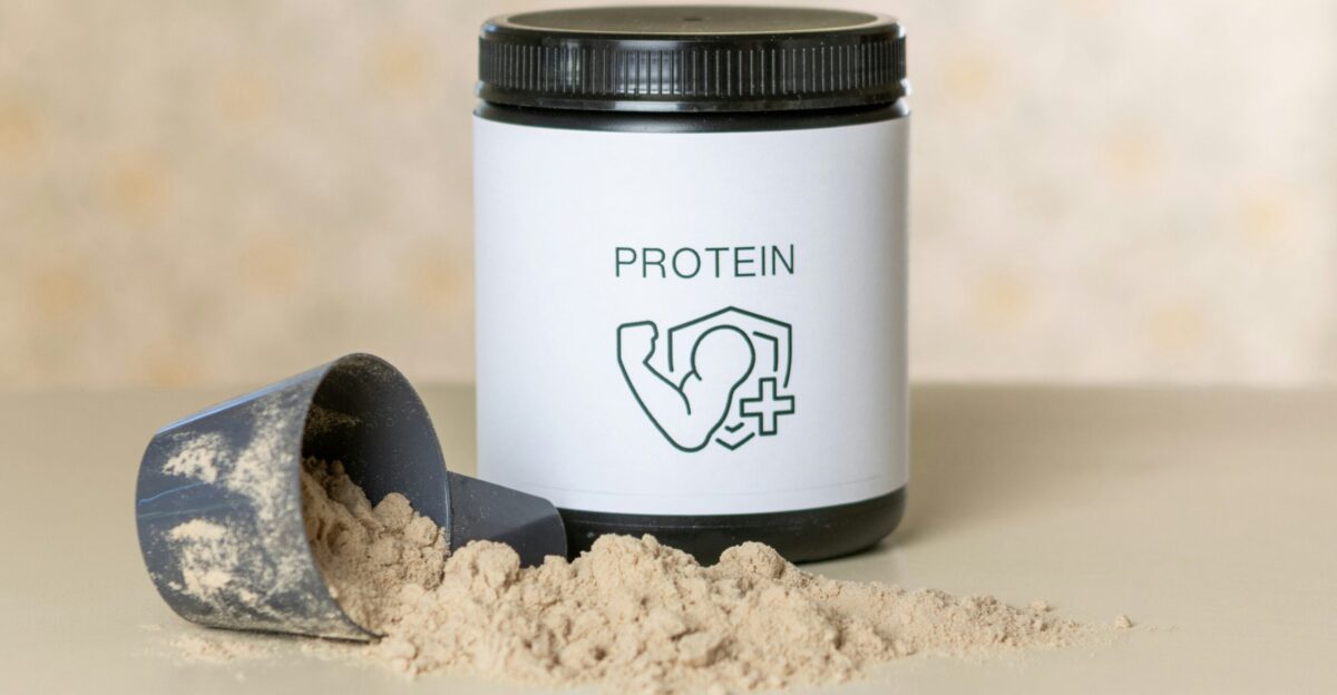 a jar of protein powder next to a scoop of powder