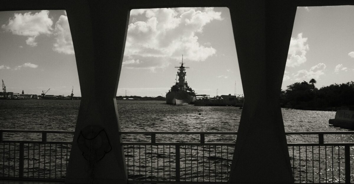 a large ship is in the water near a fence