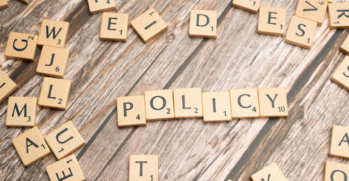 scrabble tiles spelling policy on a wooden table