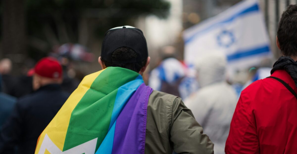 a couple of men walking down a street holding a rainbow flag