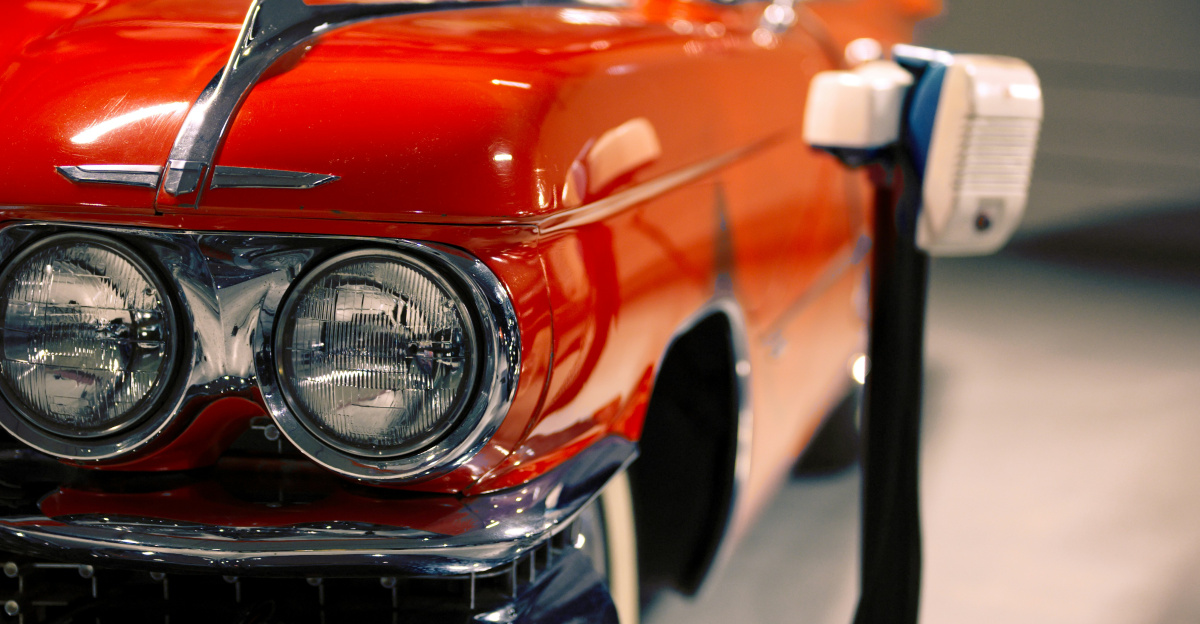 a red classic car parked next to a parking meter