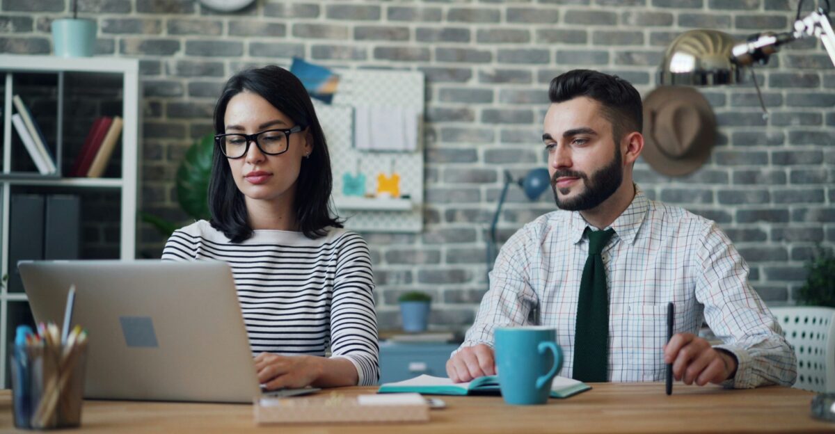 a man and a woman sitting at a table with a laptop