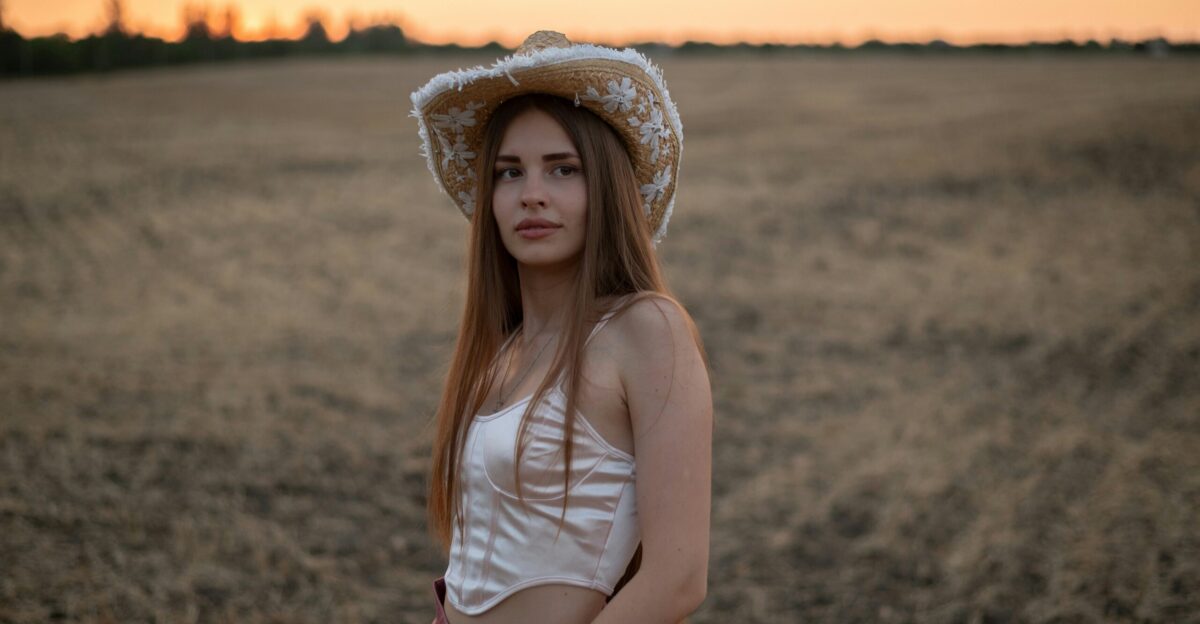 A woman standing in a field wearing a hat