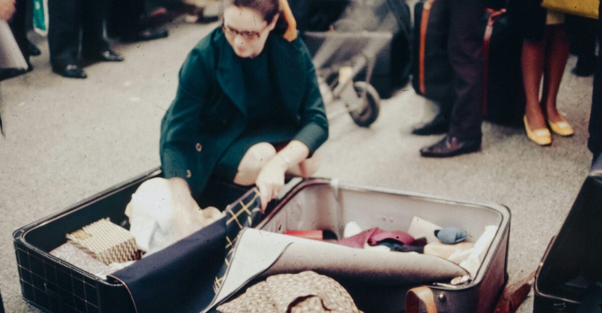 A woman sitting in an open suitcase on the ground