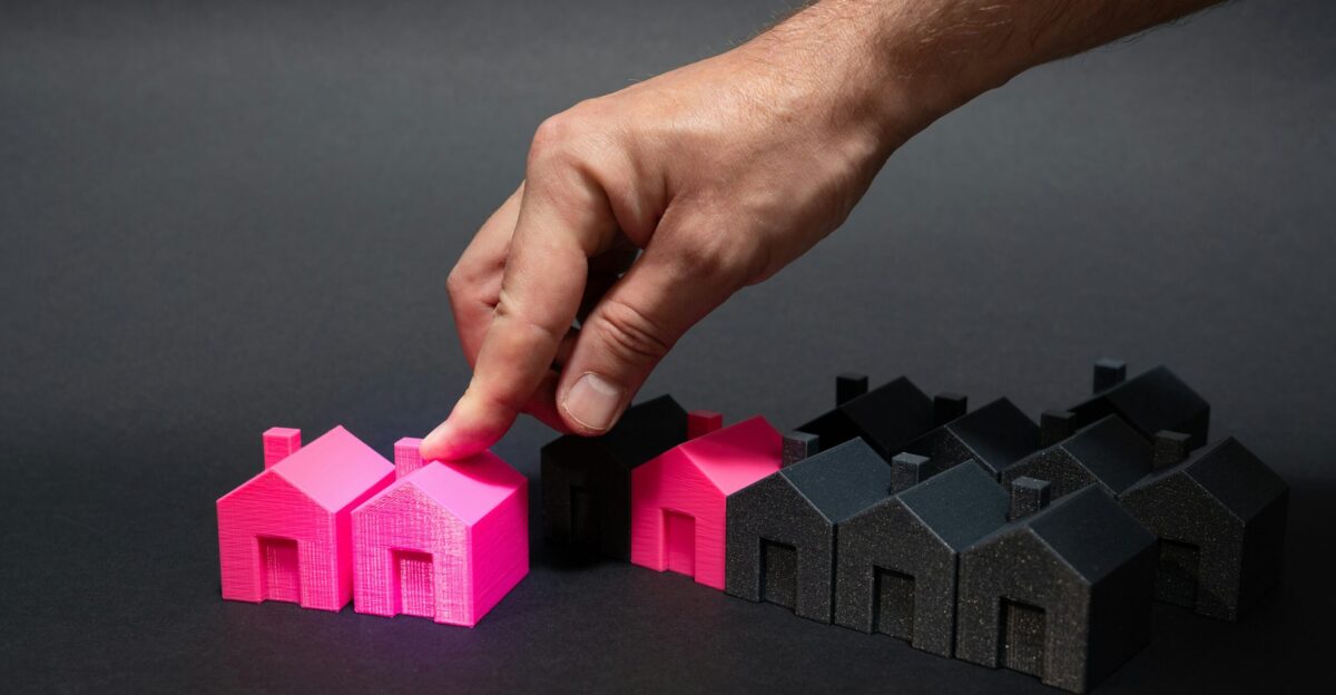 A hand is pointing at a small pink house