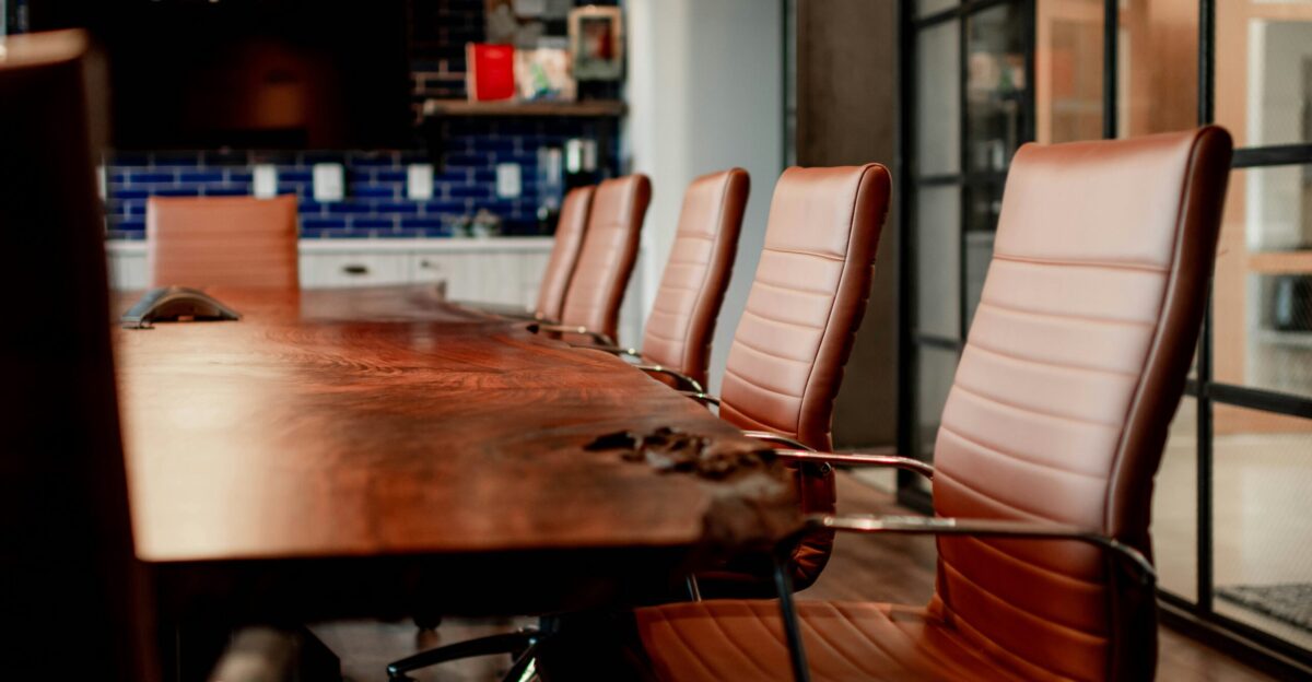 A conference room with a large wooden table and leather chairs