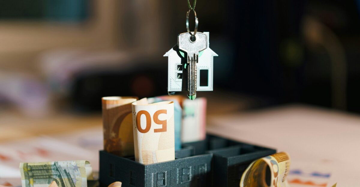 A house hanging from a string on top of a pile of money