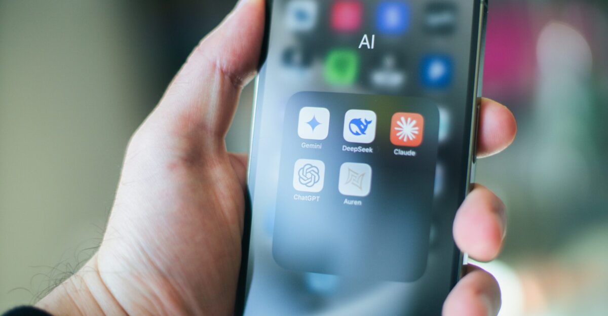 A hand holds a smartphone with various apps