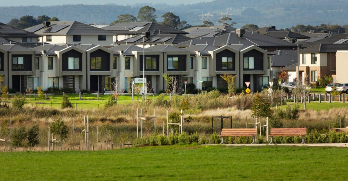 Suburban homes line a grassy area with benches