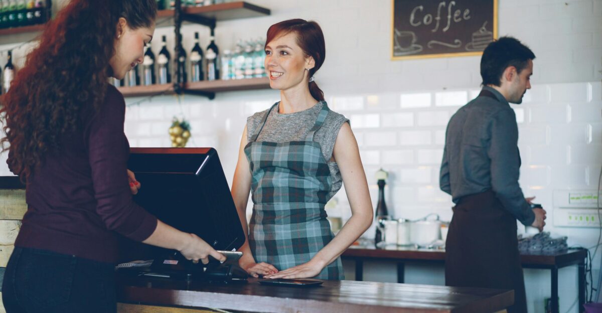 A customer pays at a coffee shop counter