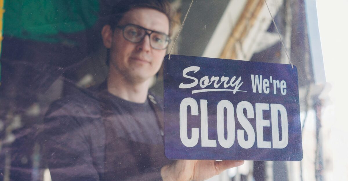 A man shows a sorry we re closed sign