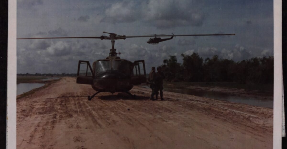 Pilot of a downed helicopter talks with the pilot of the UH-1B maintenance helicopter as a UH-1C gunship flying above protects the area NARA 111-CCV-94-CC43546