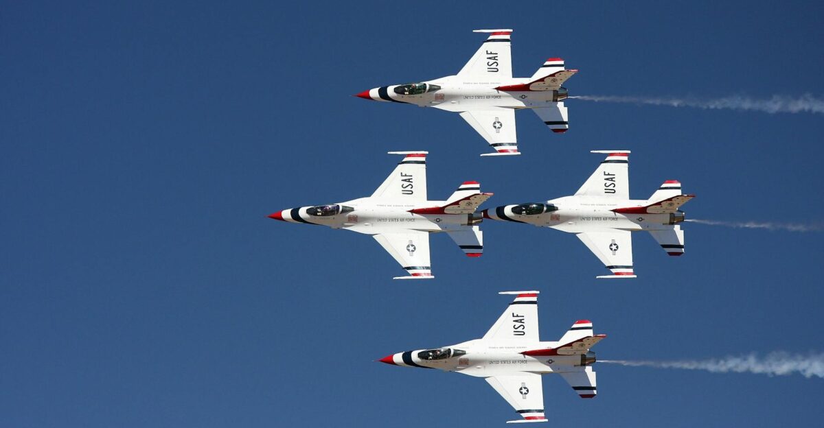 Four USAF fighter jets performing an aerial maneuver against a clear blue sky