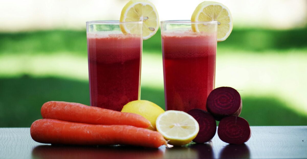 Colorful glasses of beetroot and carrot juice garnished with lemon slices symbolizing health and freshness