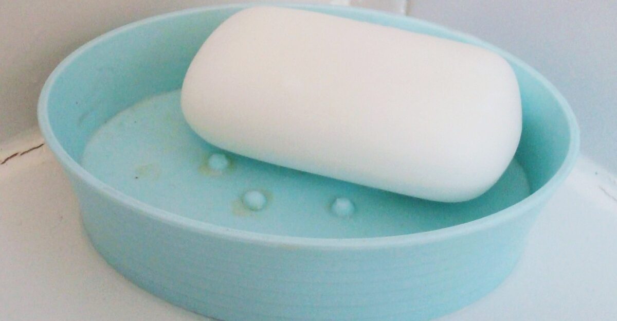 A white bar of soap in a light blue plastic soap dish