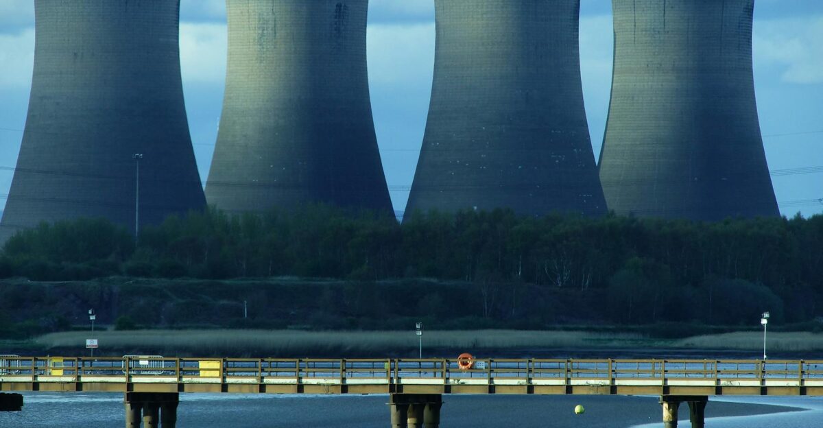 View of industrial cooling towers and a bridge over water showcasing energy infrastructure
