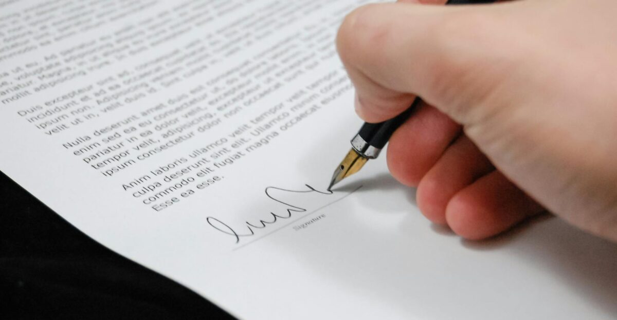 Close-up of a hand signing a legal document with a fountain pen symbolizing signature and agreement