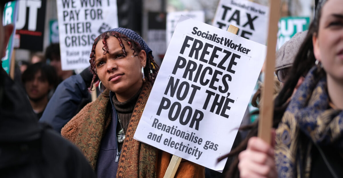 A protester opposite Downing Street listens to one of the speakers on a day of action over the surging cost of living One of the speakers was Jeremy Corbyn He reminded the crowd of the cruelty of austerity resulting in hunger and death in a country which was the fifth richest in the world We are in a crisis Corbyn declared and we are in a crisis which is of human making and not of a natural occurrence At this very moment people are faced with a massive rise in their fuel bills At the same time everyone of those energy companies are posting record and massive profits At the same time there are many people speculating on the futures on gas and on other forms of energy production as well Surely the answer to this is not to offer a tiny amelioration of the massive price rise that people are facing It s to recognise that fuel poverty means hunger Fuel poverty means death Fuel poverty means older people dying in freezing cold places because they can t afford to heat them And this in the fifth richest country in the world On the 2 April 2022 the second of two large demonstrations to be held in London this year took place - protesters were highlighting the government s complicity in the rise in the cost of living and increasing levels of inequality and poverty It was organised by the anti-austerity organisation People s Assembly and trade unions and rallies took place in several cities across the UK While the very rich have seen their wealth increase as a result of the government boosting equity markets through quantitative easing as well as massive subsidies to larger businesses the majority of the population and particularly the poor have seen their living standards decline and the current increases in energy food and other essential living costs will hit the poorest in society the hardest Labour MP Zarah Sultana tweeted The cost of living crisis is a Tory political choice they hand bankers a 1bn-a-year tax cut while scrapping the 20-a-week universal credit uplift and activist Peter Tatchell similarly declared that he had joined today s pplsassembly protest against cost of living crisis urging a WindfallTax on energy companies I also urged a one-off 20 WealthTax on UK s 171 billionaires It would raise 120bn to fund NHS social care