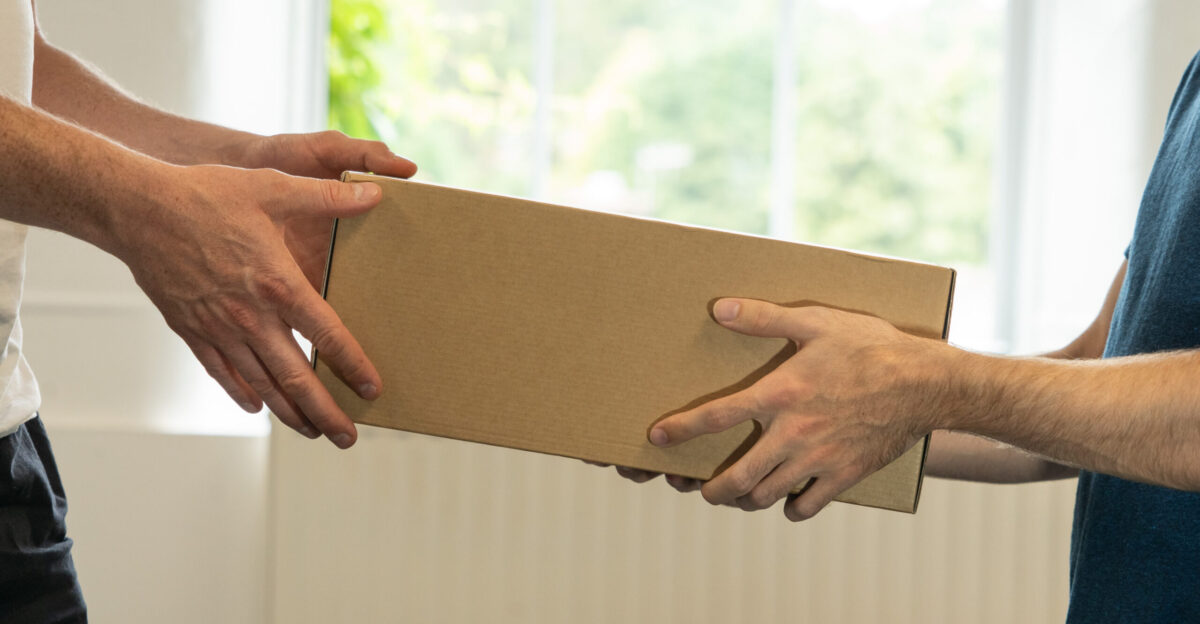 A photo of two men passing a package between them in front of a window and a radiator One of the men is slightly taller and appears to be taking the parcel from the other We have released this image under the Creative Commons Licence It s free to use but if you do use it please post a link back to us at meanwell-packaging co uk