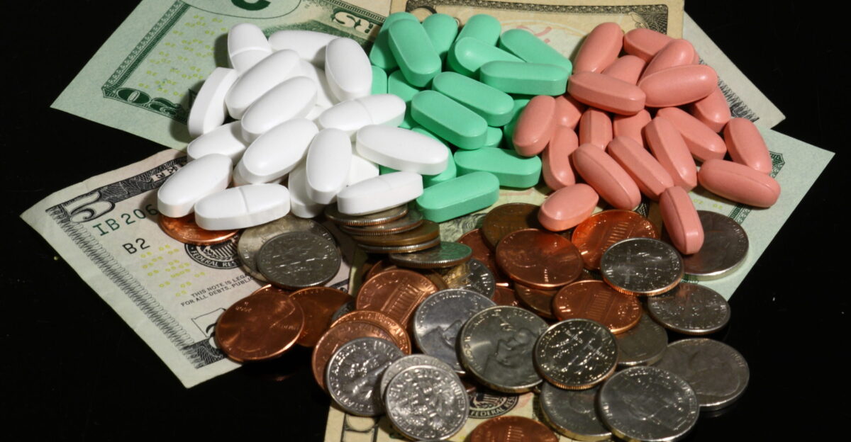 American currency bills and coins in multiple denominations and dietary supplement pills in three colors on a black background