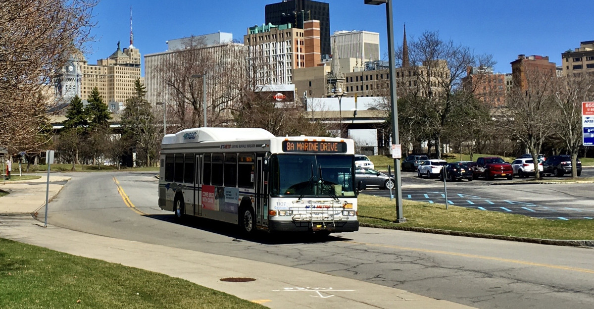 As seen at the Waterfront Village office park on a chilly April 2021 afternoon an NFTA Metro Bus on route 8 begins its outbound trip which will culminate with an arrival roughly 40 minutes later at the Main-Bailey Loop on the South Campus of the University at Buffalo