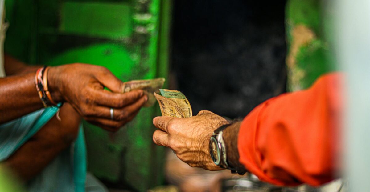 A close-up shot of two people exchanging currency in an outdoor market setting