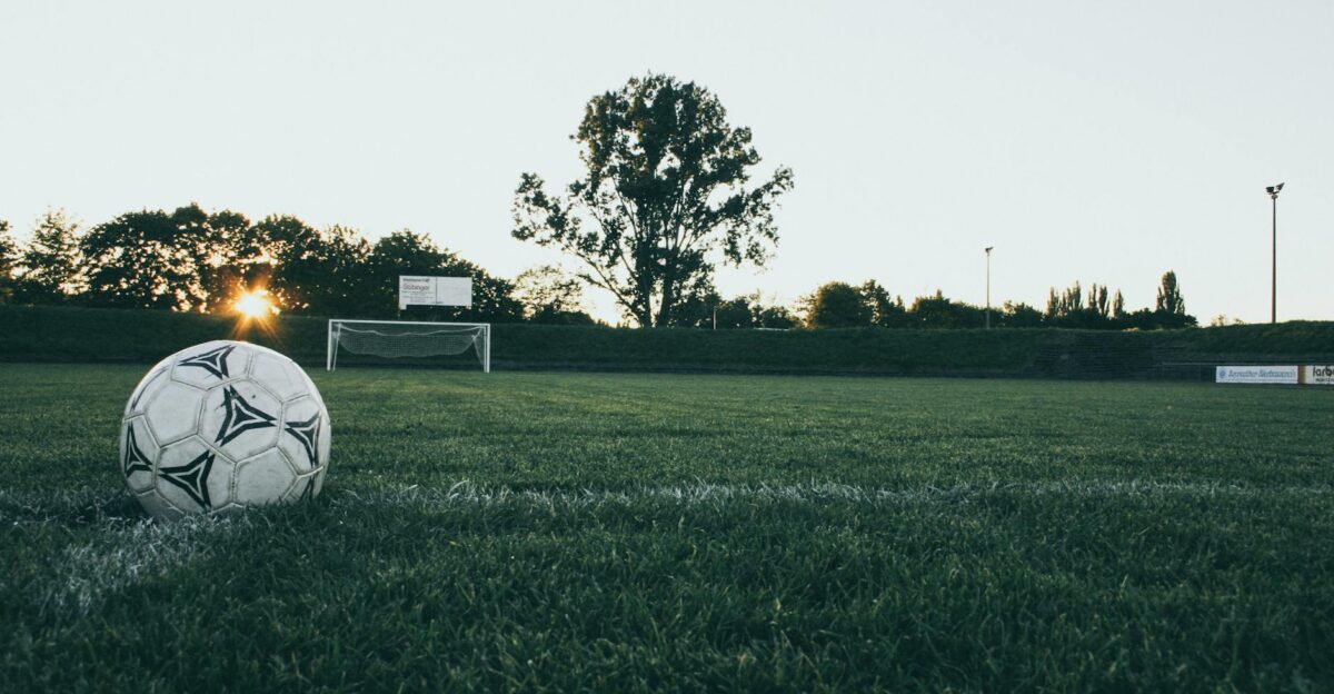 Soccer ball on field at sunrise serene landscape with goalpost in background