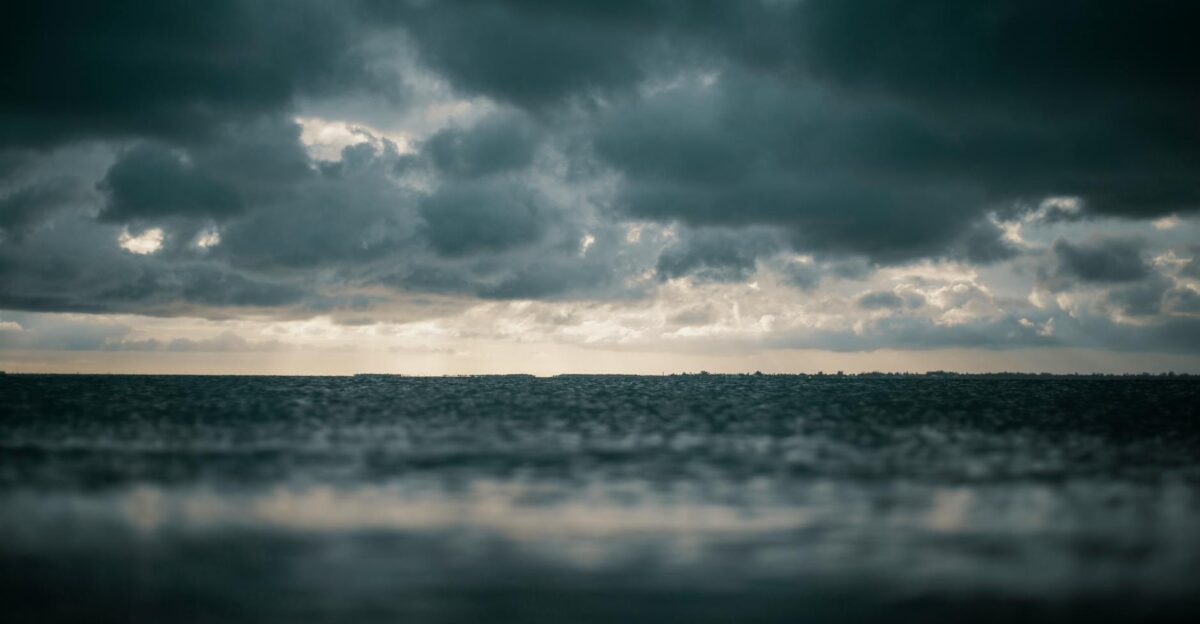 A captivating view of the ocean with dramatic dark clouds above presenting a moody and dramatic seascape