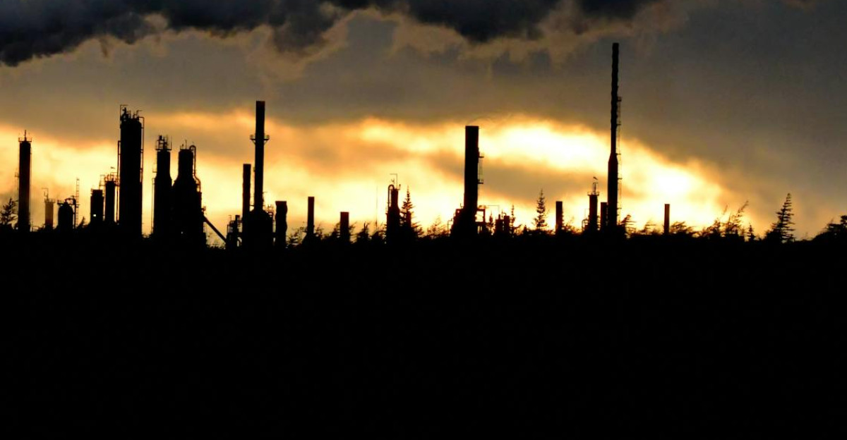 Silhouette of an industrial plant with smoke during a vibrant sunset