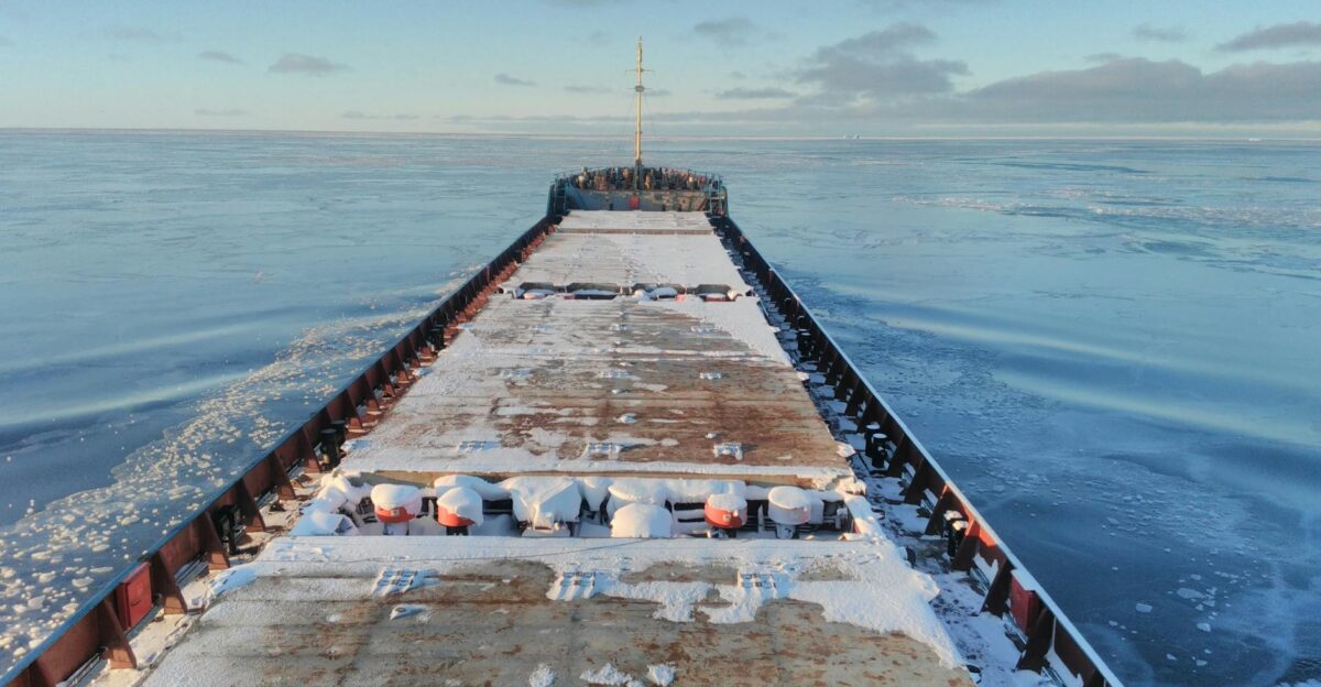 A large cargo ship breaking through icy waters in the Arctic showcasing logistics in harsh winter conditions
