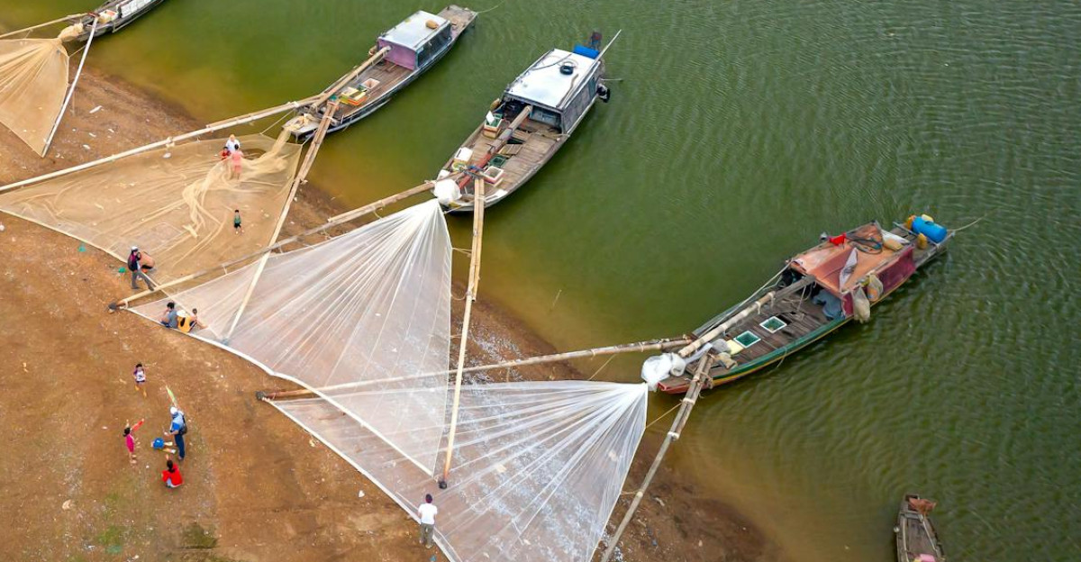 Fishing boats with nets docked at a shore in an aerial view showcasing a coastal fishing activity