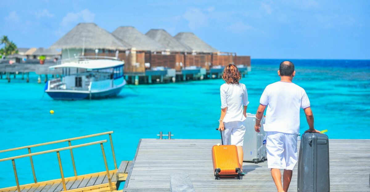 A couple arriving at a luxurious Maldives resort dock with luggage capturing a tropical vacation vibe