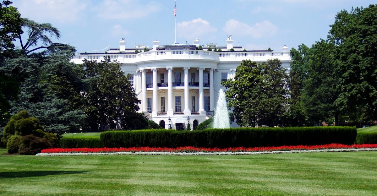 Iconic view of the White House with lush gardens and a central fountain on a sunny day