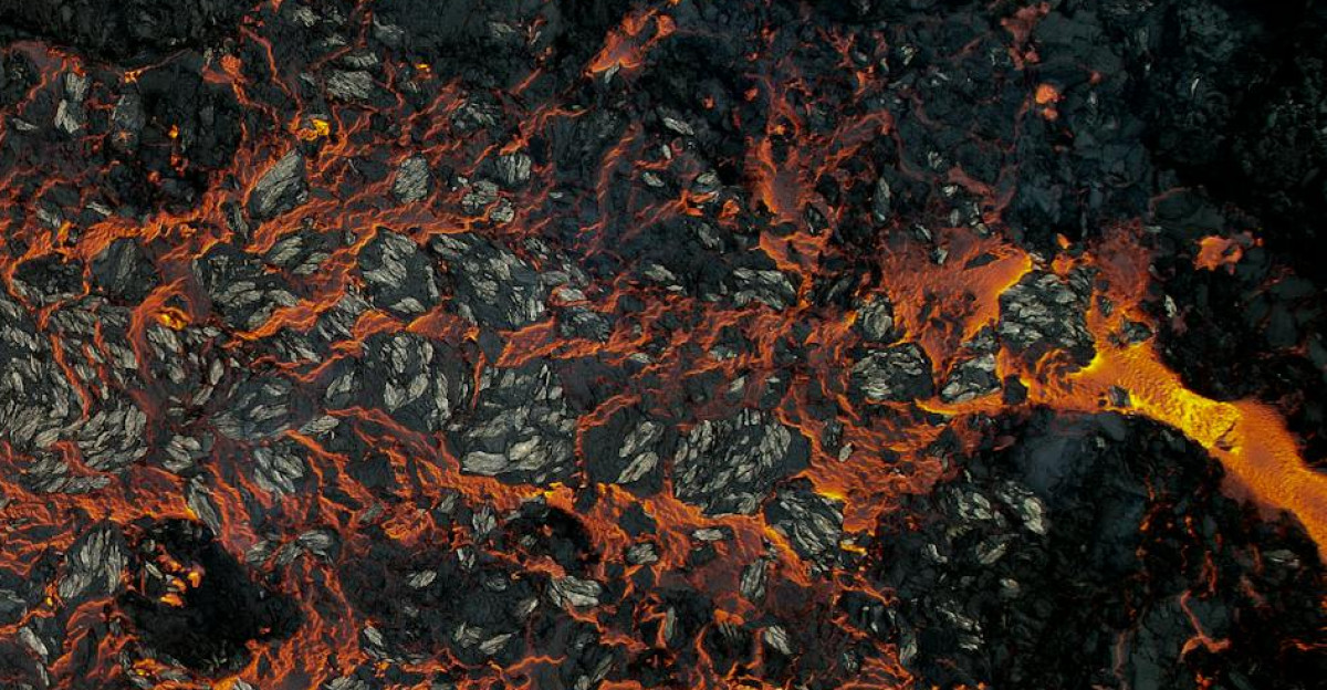 Stunning aerial shot of lava flowing across dark volcanic rocks in Iceland