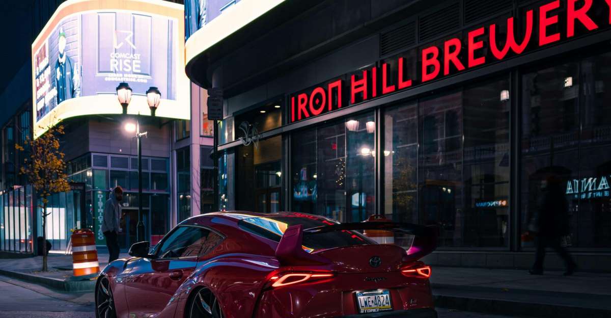 A vibrant red sports car parked near Iron Hill Brewery, Philadelphia at night.