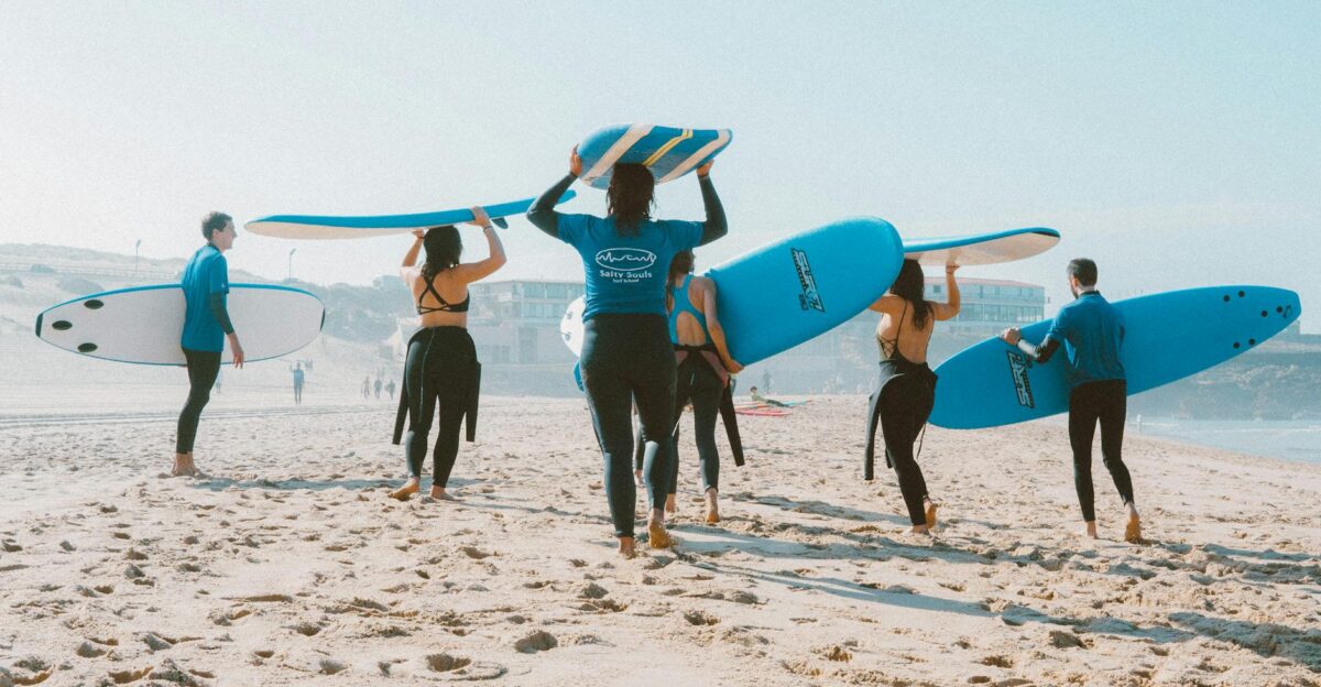 Group of surfers with blue surfboards heading to the ocean on a sunny beach
